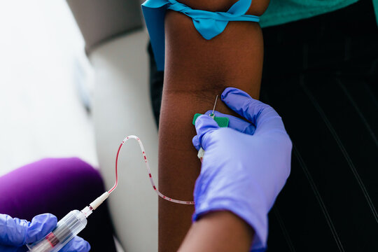 Black nurse collects blood sample from female patient at doctors office