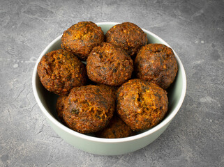 Vegan falafel balls in a bowl on a cement surface