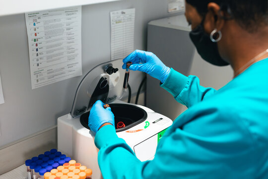 Black healthcare professional uses centrifuge machine in laboratory at medical facility