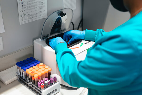 Black healthcare professional uses centrifuge machine in laboratory at medical facility