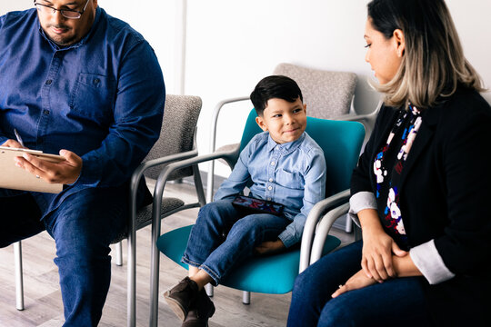 Latino father and family completing spanish translated medical forms at doctor office