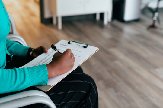 Black woman completing medical paperwork and healthcare forms on clipboard
