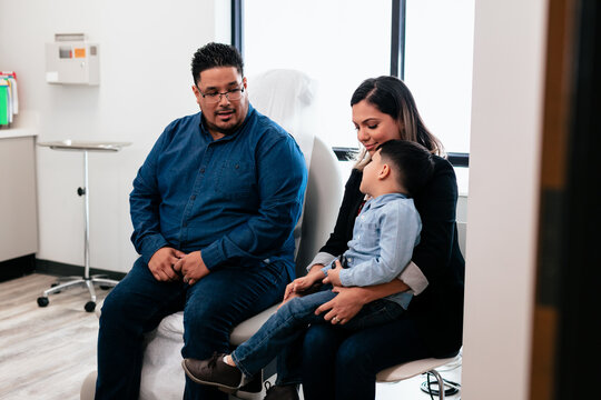 Hispanic family at doctor office waiting in exam room for a medical appointment