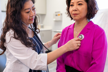 Asian doctor checks patient heartbeat using stethoscope