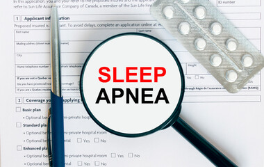 Magnifying glass with text Sleep Apnea inside lies on medical documents with pills and a blue metal pen