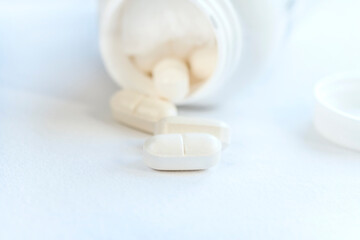 Fototapeta na wymiar White pills and bottle on a white background, close up, isolated