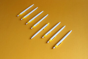 Fountain pens lie in a row on a yellow background, top view, space for text
