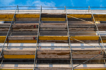 Metal-wood scaffolding on the facade of an apartment building against the sky outside