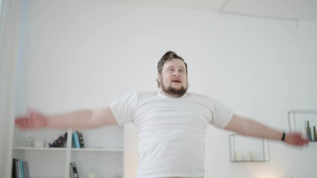 Obese male jumping, doing morning exercises at home, fitness training, sport