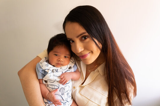 beautiful portrait of a young hispanic mother with her newborn baby