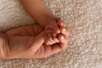 parents hands holding their baby's hand