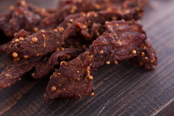 Organic Dried Pork with Pepper Dried Seal, Studio Shot. Jerky on sacking. Wooden background. 