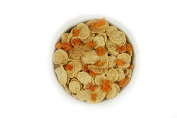 A bowl of cornflakes with dried apricots, top view. Isolated