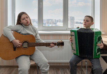 a boy and a girl sing a duet while playing the guitar and accordion while studying at a music school