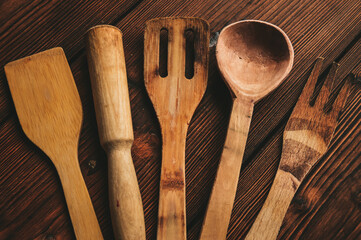 Wooden kitchen utensils on a wooden background. Handmade spoon. Pusher, spatula and spoon made of...