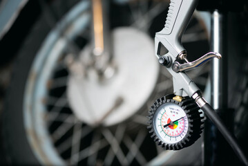 A motorbike wheel and car tyre inflation gun on the floor.