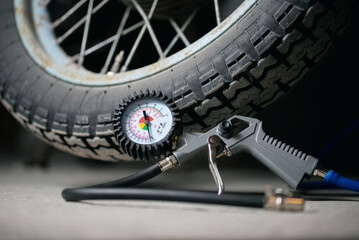 A motorbike wheel and car tyre inflation gun on the floor.