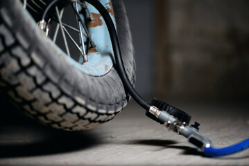 A motorbike wheel and car tyre inflation gun on the floor.