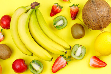 Ripe Juicy Tropical Summer Seasonal Fruits Mango  Coconut Kiwi Bananas Strawberries on yellow Background. Vacation Healthy Lifestyle Superfoods