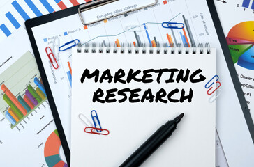 On the table are reports, charts, a notebook with the inscription - MARKETING RESEARCH