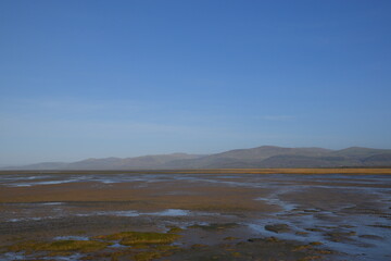the smooth wet sand at the end of an estuary with the mountains in the background