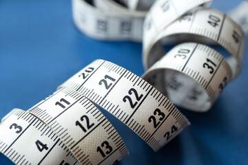 Centimeter tape, fitness and weight loss. Tailor's meter, for sewing, on a blue background. Meter, tape measure, to measure the body, waist in centimeters.
