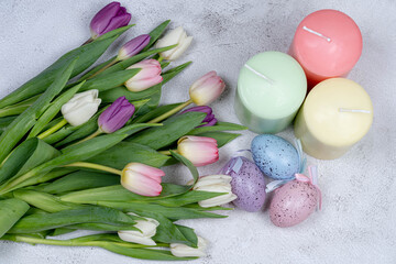 Easter eggs, candles, a bouquet of tulips from above on a gray background. Happy holiday concept ER
