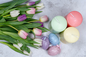Easter eggs, candles, a bouquet of tulips from above on a gray background. Happy holiday concept ER