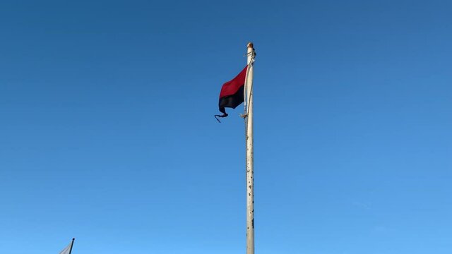 Bandera roja y negra flameando contra el viento /  Red and black flag fluttering against the wind