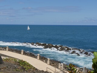 Fototapeta premium Rocky coastal area with foaming waves at the walkway behind the