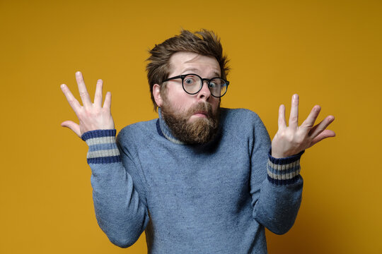 The strange, surprised man shrugs his shoulders and makes a bewildered hand gesture. Yellow background.
