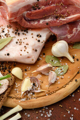 Fototapeta na wymiar raw pork meat and lard with salt, spices and garlic on a cutting board, dark wooden background