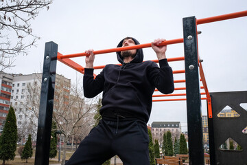 Fototapeta na wymiar Young man making pull-up exercises on the crossbar outdoors. Fitness, sport, exercise, training and healthy lifestyle concept