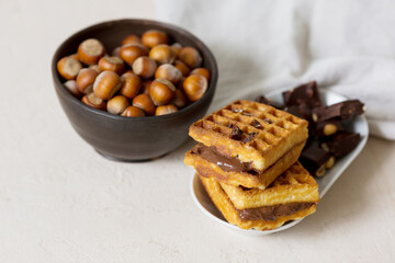 Waffles with chocolate nut spread. Cup with hazelnuts, hazelnut