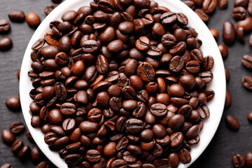 Cup of coffee with beans on table, top view 