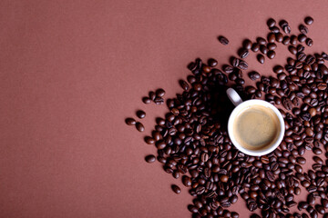 Coffee mug with roasted beans on stone background. Top view with copy space