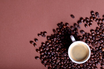 Coffee mug with roasted beans on stone background. Top view with copy space