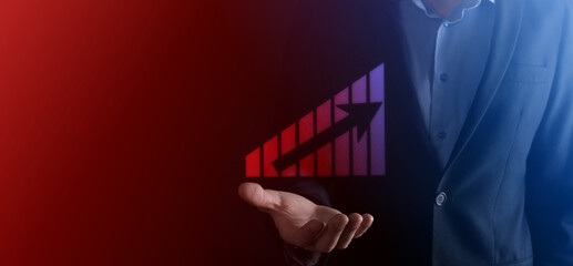 Business man holding holographic graphs and stock market statistics gain profits. Concept of growth planning and business strategy. Display of good economy form digital screen.