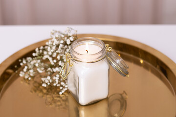 Beautiful candle light with white flowers on golden plate, romantic background