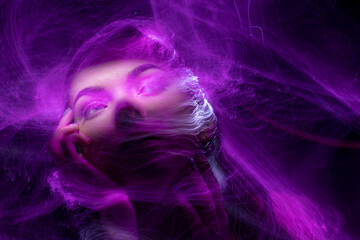 beautiful girl model with cosmic make-up on face, blue and purple color on dark background ,...