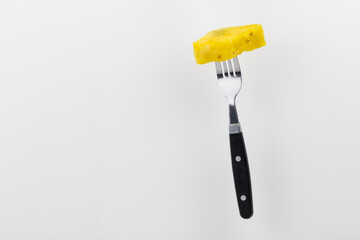 Isolated piece of pineapple fruit on a fork on white background.