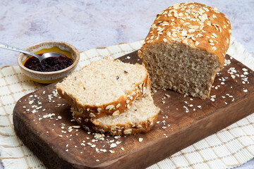 Chopped oat bread on a wooden and stone background with blackberry jam