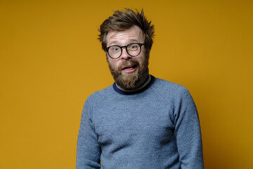 A strange shaggy man with glasses, with a stupid expression on his face, looks at the camera in...