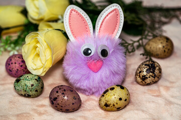 toy fluffy easter bunny sitting next to carrots, easter eggs and flowers