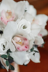 Wedding bridal bouquet of white orchids on a wooden surface. Close-up.