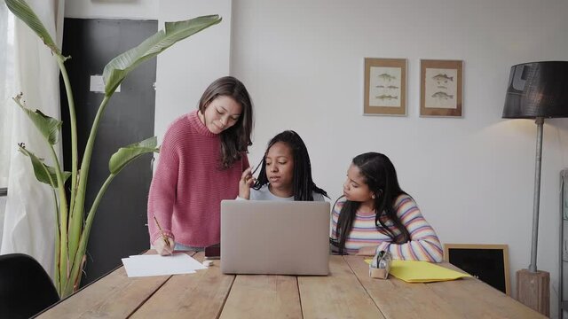 In the office: three women work together without masks or safety measures. They discuss work issues amicably while looking at the computer screen.