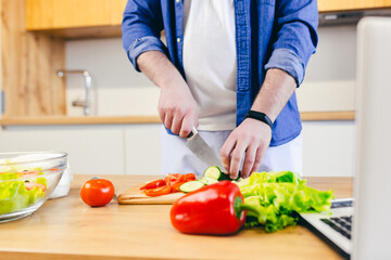Close-up photo, a man at home chops vegetables in the kitchen, prepares breakfast