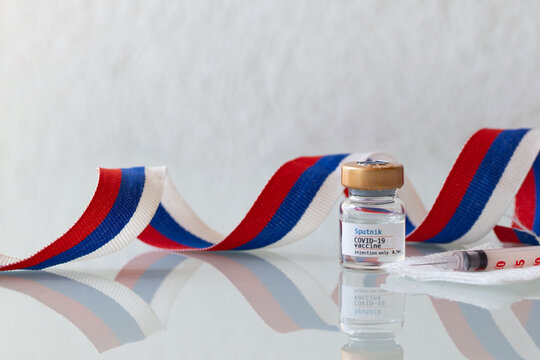 Leisach, Austria. March 18th, 2021. Glass vial of Sputnik COVID-19 vaccine and Russian flag ribbon as a background. Closeup