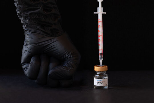 Leisach, Austria - March 18th, 2021. Glass vial of Sputnik COVID-19 vaccine and human wrist in rubber glove. Closeup