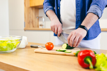 Close-up photo, a man at home chops vegetables in the kitchen, prepares breakfast